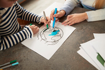 Hands of girls coloring planet earth with pens at home