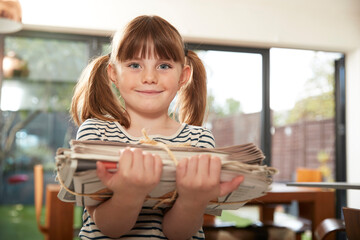 Smiling cute girl with newspapers at home