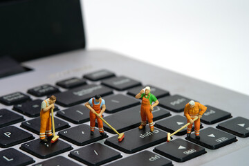 Miniature people toy figure photography. Group of sweeper workers cleaning notebook laptop keyboard...