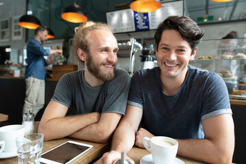 Smiling man with friend sitting in coffee shop