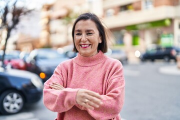 Middle age woman smiling confident standing with arms crossed gesture at street