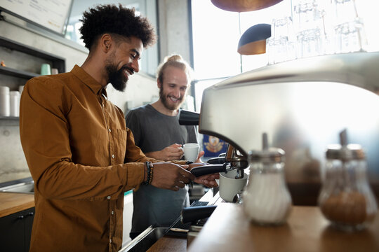 Happy baristas making coffee together in cafe - Powered by Adobe