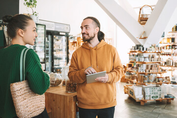 Man with tablet PC talking to woman in convenience store