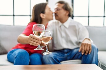 Middle age man and woman couple kissing and toasting with champagne at home