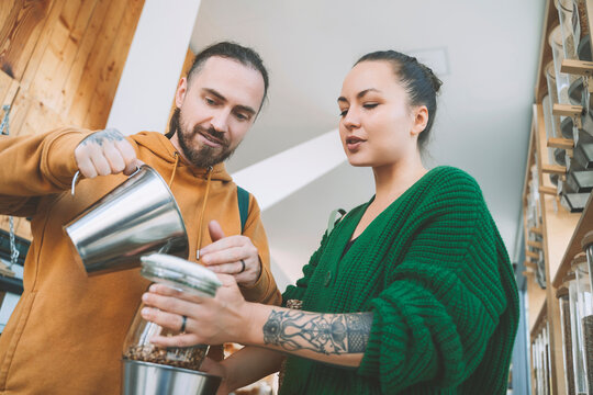 Man Helping Woman To Fill Jar In Retail Store