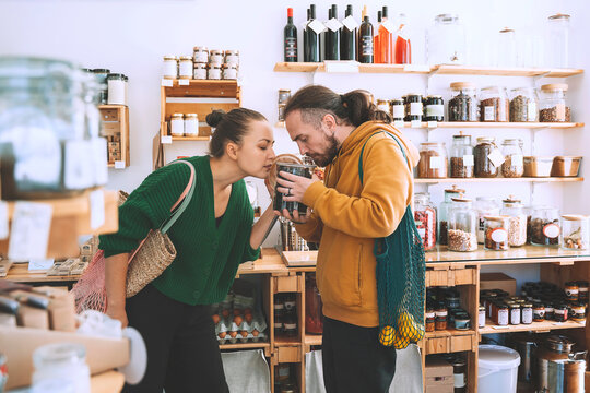 Customers smelling dried food in jar at convenience store