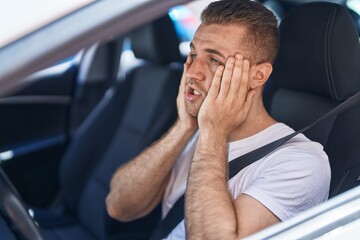 Young caucasian man stressed driving car at street