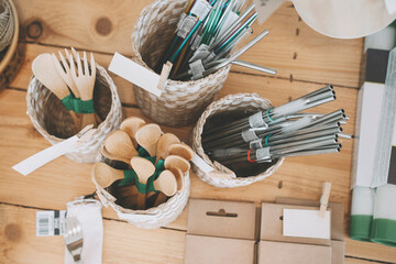 Varieties of wooden cutleries and steel straws in baskets on table at store