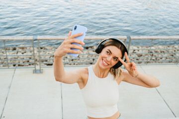 Young sportswoman taking selfie photo while doing workout at embankment