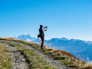 Senior man photographing through smart phone on sunny day at Vanoise national park, France