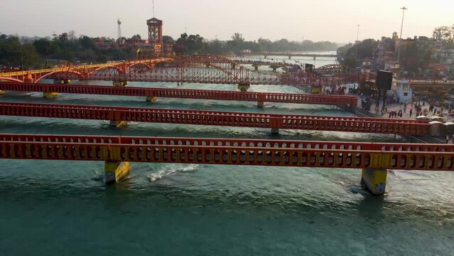 isolated iron bridge many over ganges river with wide view of city at riverbank at evening aerial video is taken at har ki pauri haridwar uttrakhand india on Mar 15 2022.