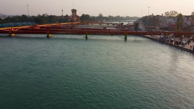 isolated iron bridge many over ganges river with wide view of city at riverbank at evening aerial video is taken at har ki pauri haridwar uttrakhand india on Mar 15 2022.
