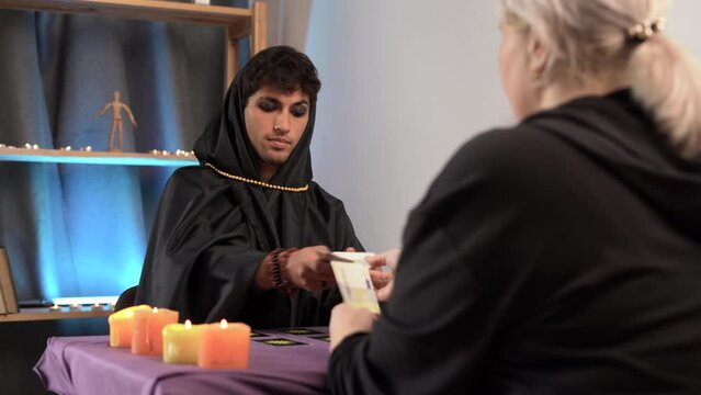Male sorcerer tarot card reader predicts the future at a tarot session