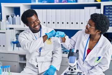 African american man and woman scientists bump fists at laboratory
