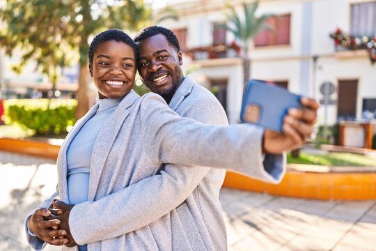 Man and woman couple standing together make selfie by the smartphone at park