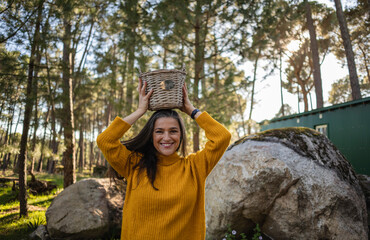 Smiling mature woman holding a wicker basket on top of her head