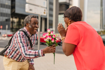 Senior man surprising woman with bunch of flowers