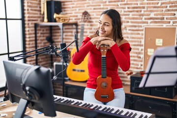 Young african american woman musician smiling confident holding ukelele at music studio