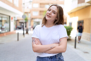 Fototapeta premium Young caucasian woman standing with arms crossed gesture at street