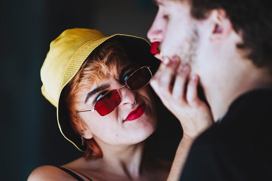 Young girlfriend wearing sunglasses holding boyfriend's face