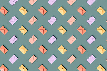Three dimensional pattern of rows of pastel colored envelopes flat laid against green background