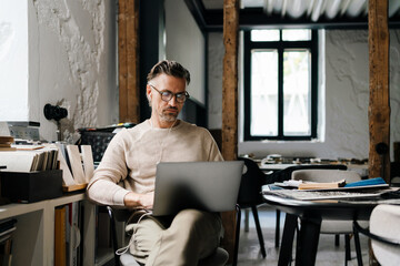 White middle-aged man using laptop computer in office