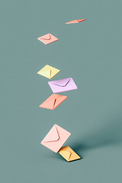 Three dimensional render of pastel colored envelopes falling down against green background