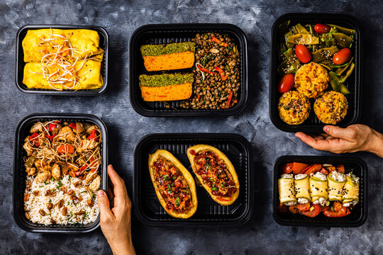Studio shot of variety of take out food including chop suey, stuffed potatoes, fajitas, rice muffins, ricotta rolls, various salads and terrine