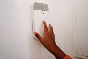 Hand of girl putting code in alarm system at home