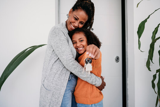 Happy Mature Woman Hugging Daughter Showing House Keys