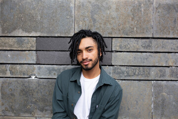 Young man with dreads in front of wall