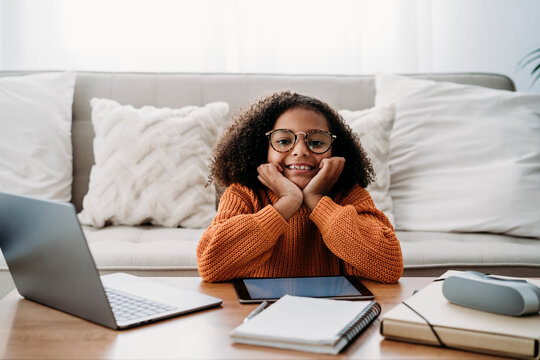 Happy girl wearing eyeglasses sitting in living room at home