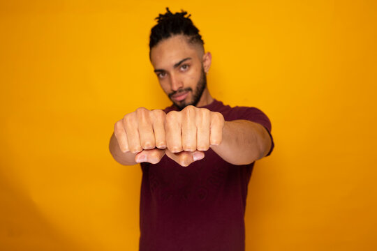 Confident man showing fists against yellow background