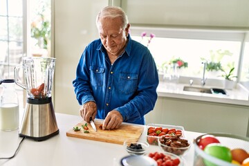 Senior man smiling confident cutting datil at kitchen