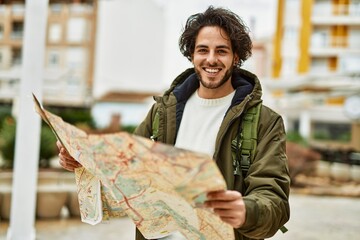 Handsome hispanic man looking at travel map at the city