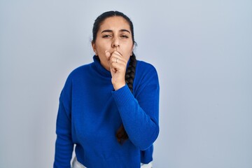 Young hispanic woman standing over isolated background feeling unwell and coughing as symptom for cold or bronchitis. health care concept.