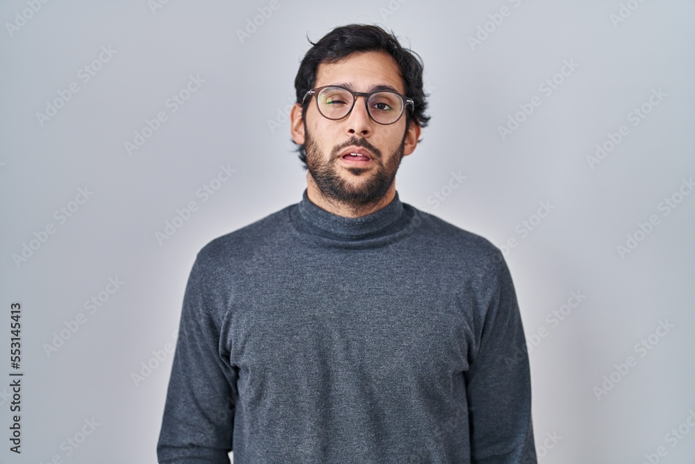 Sticker handsome latin man standing over isolated background looking sleepy and tired, exhausted for fatigue