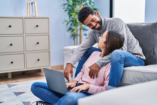 Man and woman couple sitting on sofa using laptop at home