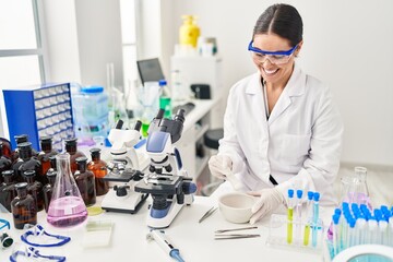 Young beautiful hispanic woman scientist smiling confident mixing sample at laboratory