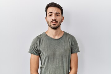 Young hispanic man with beard wearing casual t shirt over white background relaxed with serious expression on face. simple and natural looking at the camera.