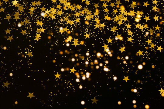 gold star confetti and glitter on a black background - Christmas or New Year party festive backdrop