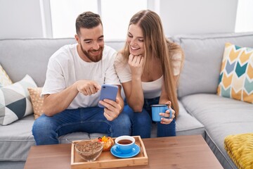 Obraz na płótnie Canvas Man and woman couple having breakfast using smartphone at home