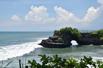 Waves crushing into a natural stone bridge at Tanah Lot temple, Bali, Indonesia