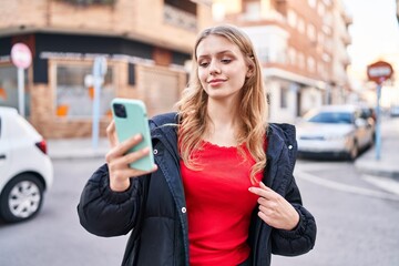 Young blonde woman smiling confident having video call at street