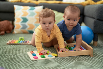 Two toddlers playing with maths toys sitting on floor at home