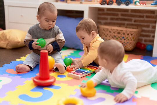 Group of toddlers playing with toys sitting on floor at kindergarten