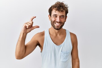 Fototapeta premium Young handsome man standing over isolated background smiling and confident gesturing with hand doing small size sign with fingers looking and the camera. measure concept.