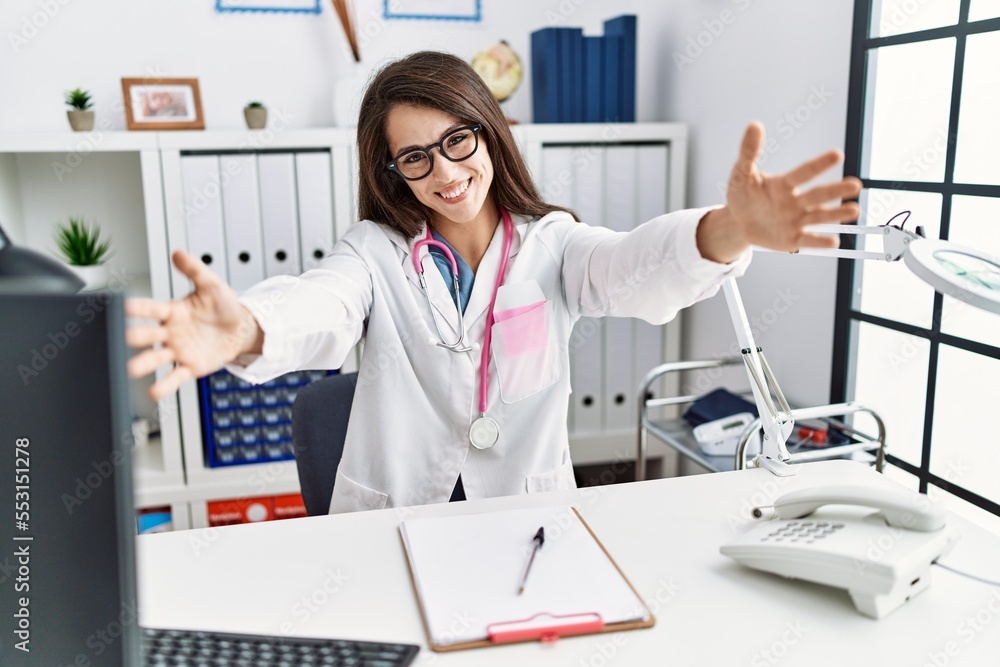 Sticker young doctor woman wearing doctor uniform and stethoscope at the clinic looking at the camera smilin