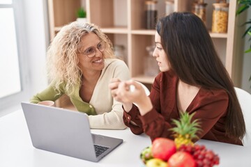 Two women mother and daughter using laptop at home