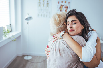 The elderly woman enjoys an embrace from her favorite home healthcare nurse. Medical care, young female doctor hugging patient. Empathy concept. Elderly woman hugging caregiver
